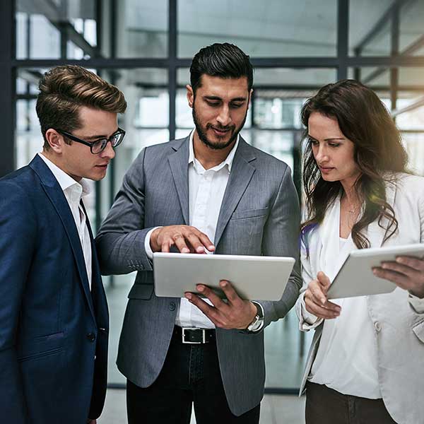 Group of colleagues using digital tablet together at work